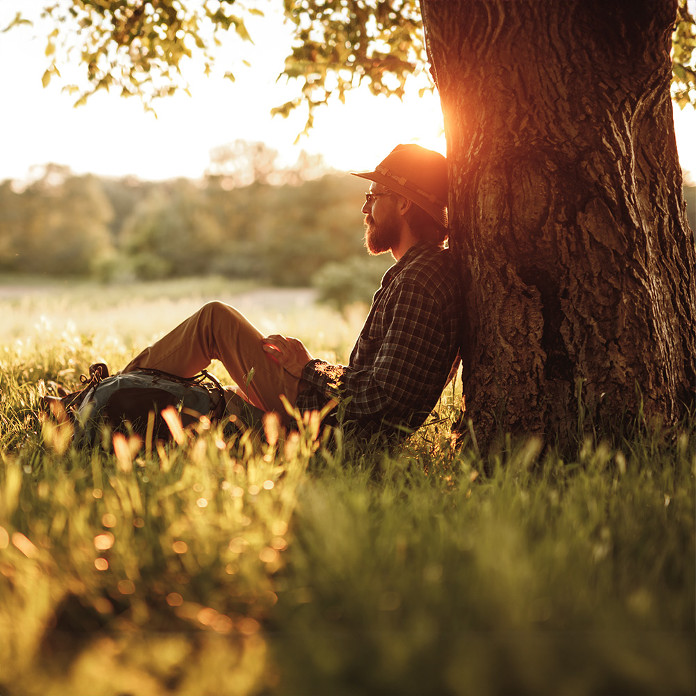 A relaxed man leaning against a tree after receiving anxiety therapy.