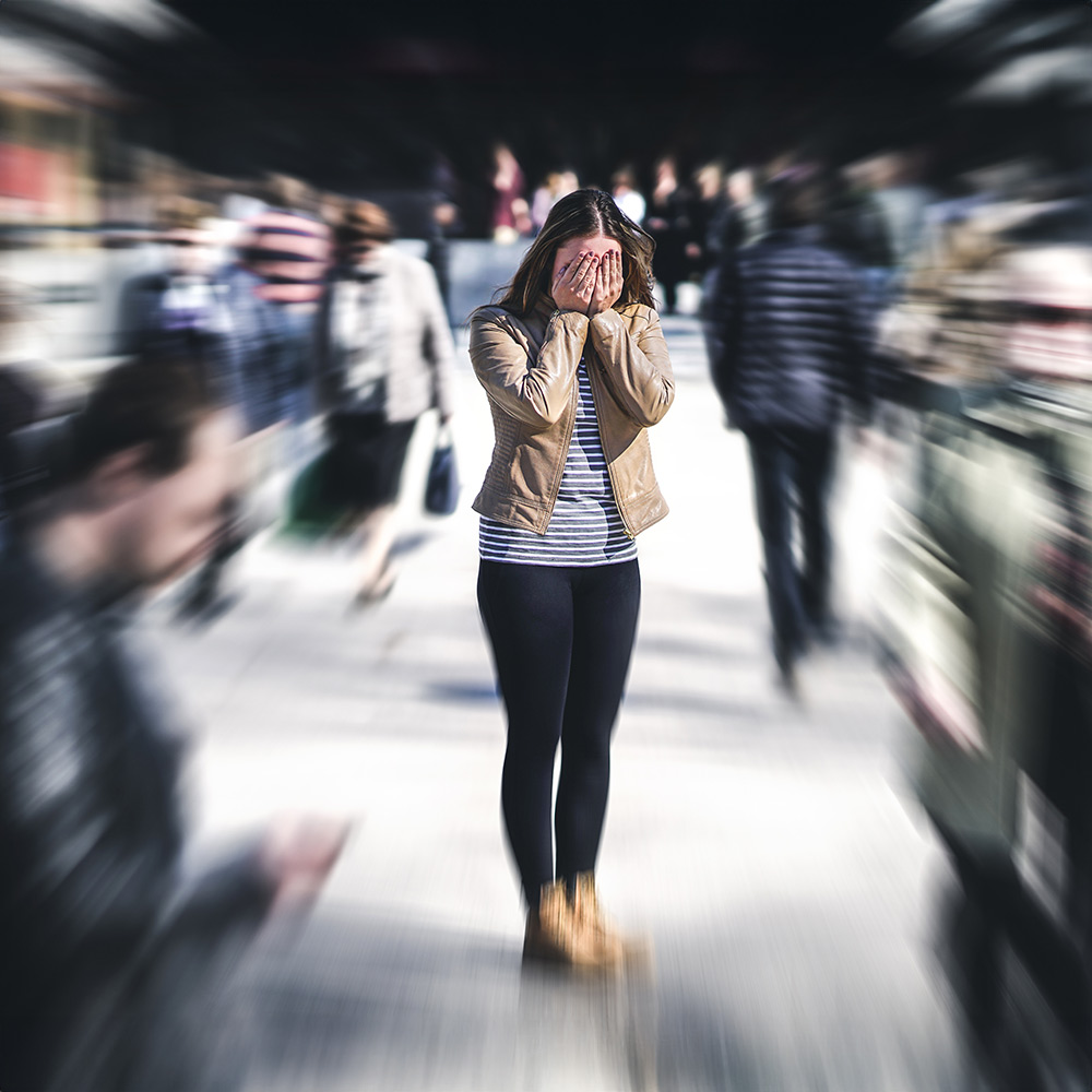 An anxious woman that is covering her face in need of anxiety therapy.